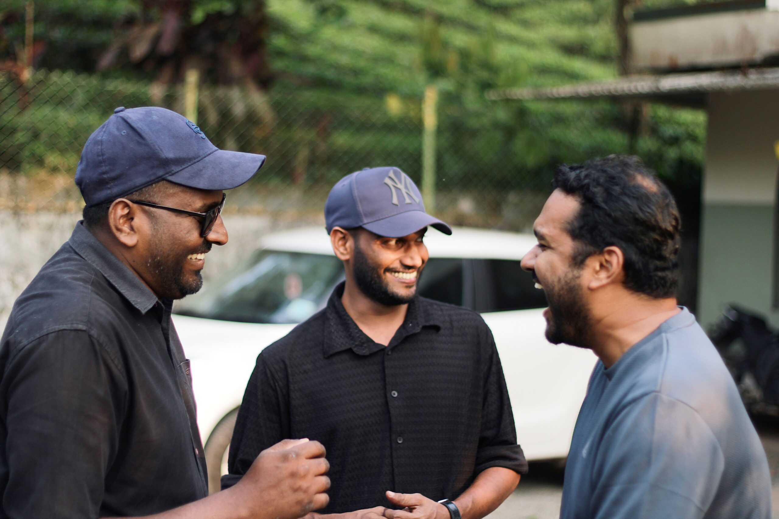 Three men enjoy a shared moment of laughter outdoors, capturing camaraderie in natural light.